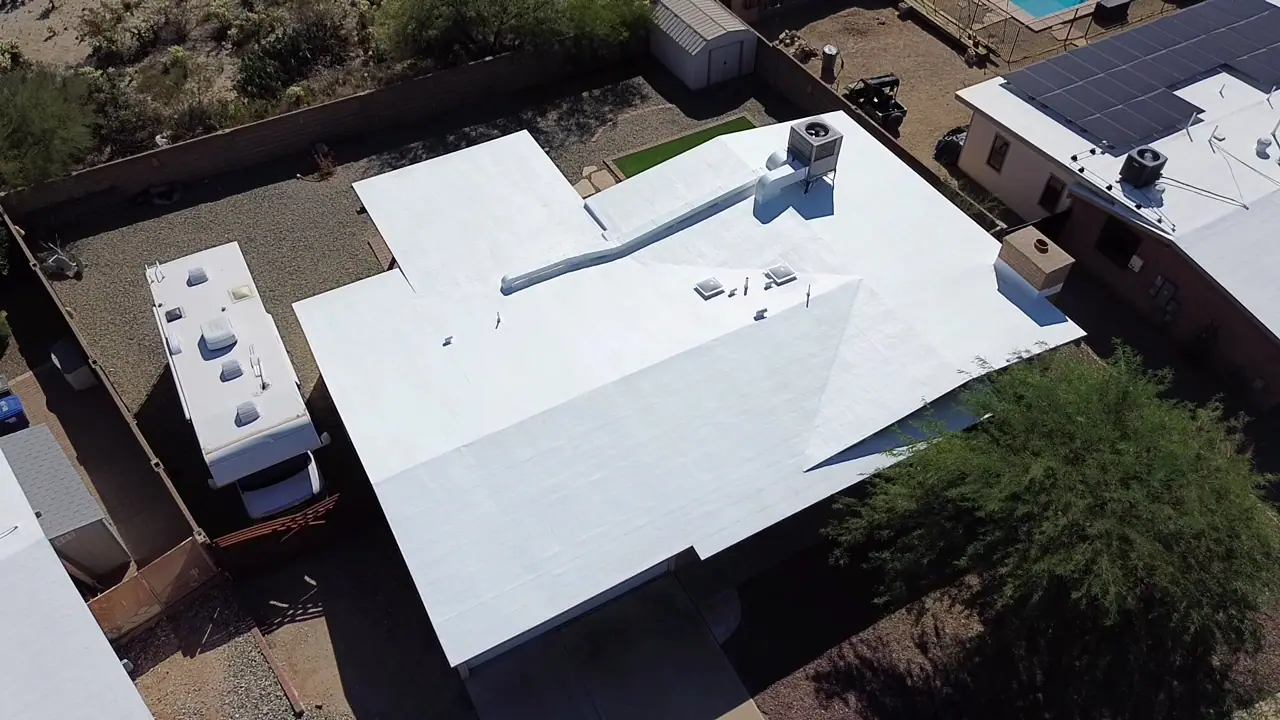 Aerial view of a home with a freshly coated white flat roof